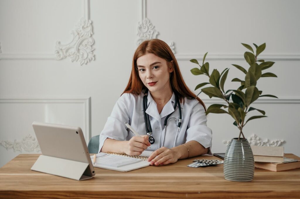 pexels-photo-5407217 Young female doctor writing notes on a tablet in a modern office setting.