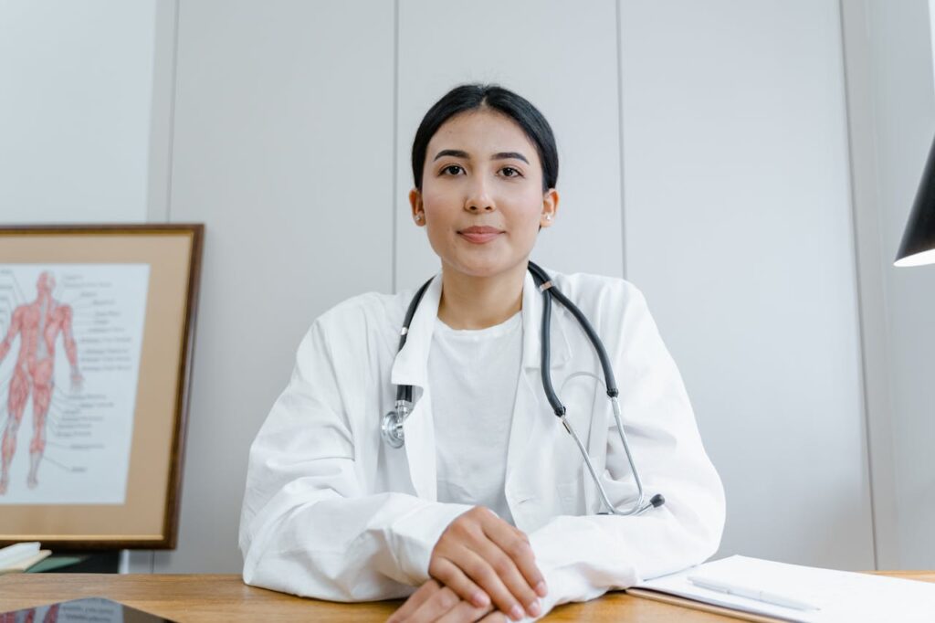 pexels-photo-8376277 A female doctor confidently sits at her desk, ready for consultation in a medical office.